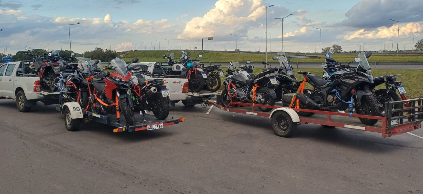 Loaded adventure motorcycles on trailers before a route departure