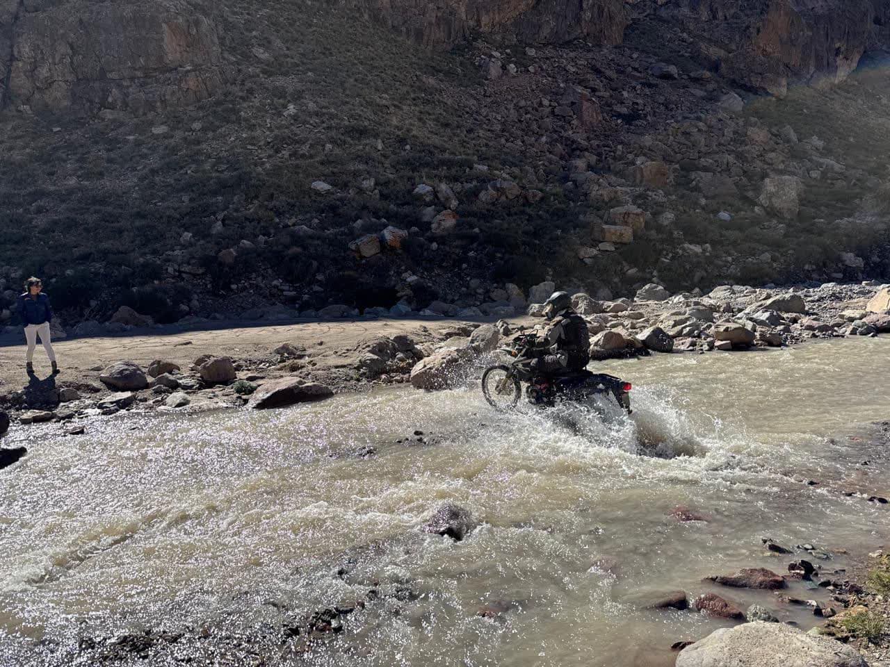 Rider crossing water on a motorcycle during the build of Cruces del Sur.