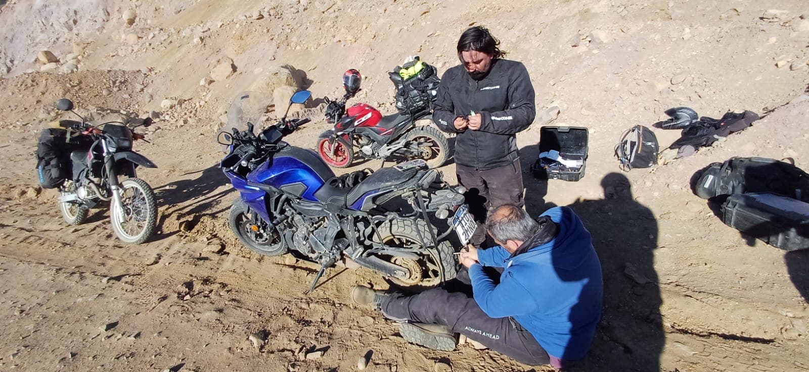 Equipe consertando uma moto em uma encosta seca durante uma exploração de Salta e Jujuy.