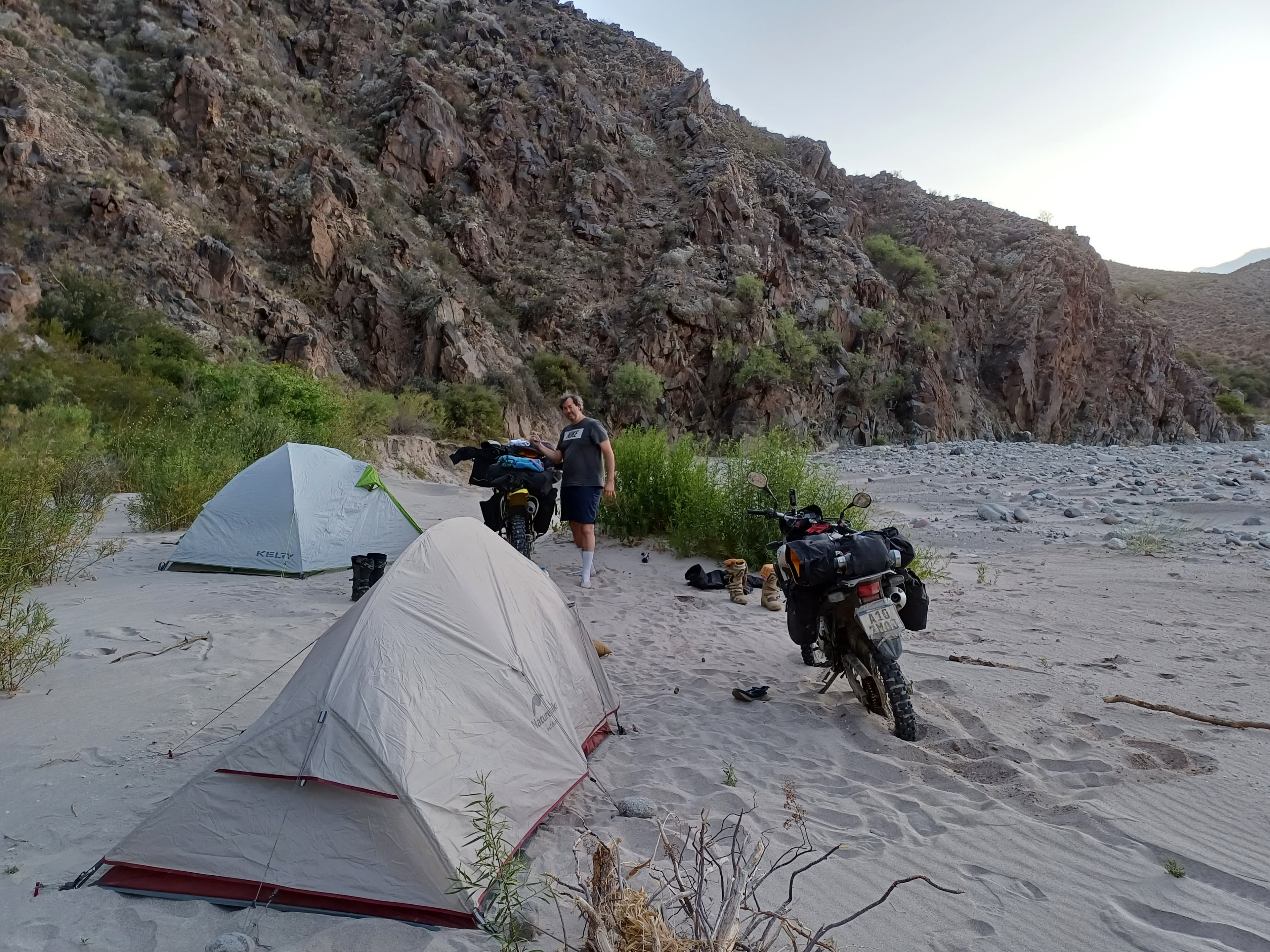 Motorcycle camp in a sand field between Catamarca rock walls.